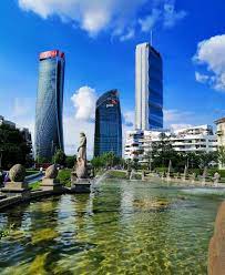 image of city life buildings from near park showing full buildings with buldings around